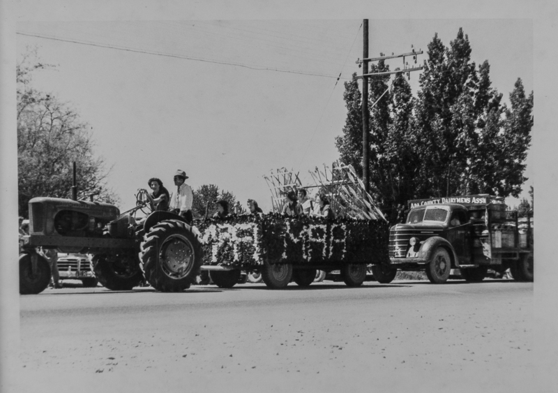 A flowered float for the Meridian Athletic Association pulled by a tractor, along with the Ada County Dairymen's Association.