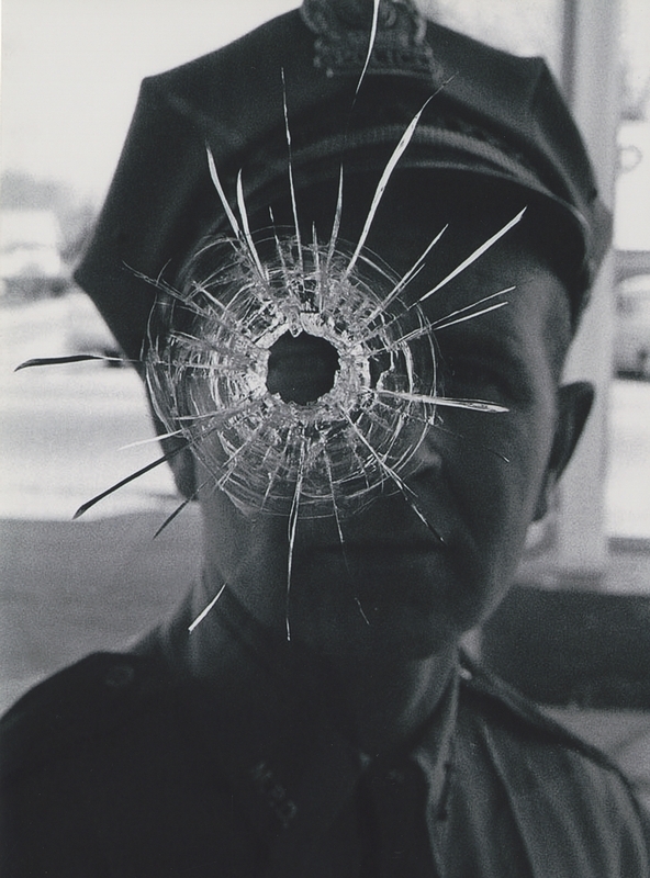 Gene Hiner inspects bullet hole in store window after shooting at suspects during a burglary in progress in April 1969