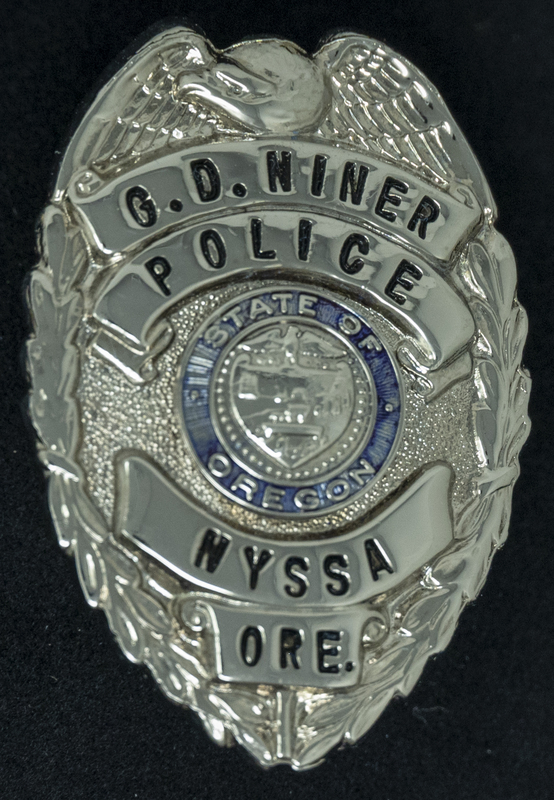 Gene Hiner Nyssa Oregon Police pin from 1961-1962, when Hiner served in the Nyssa Oregon Police Department. Part of the Gene Hiner Police Career Display presented to the MPD by Gene Hiner's family. 