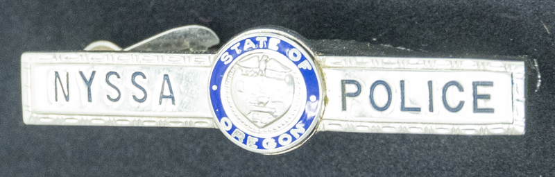 Gene Hiner Nyssa Police tie clip, from 1961-1962 when Hiner served in the Nyssa Oregon Police Department. Part of the Gene Hiner Police Career Display presented to the MPD by Gene Hiner's family. 