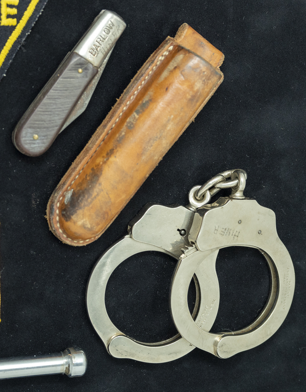 Gene Hiner knife, sheath, and handcuffs, which could have been used at anytime during his 1954-1973 police career. Part of the Gene Hiner Police Career Display presented to the MPD by Gene Hiner's family. 