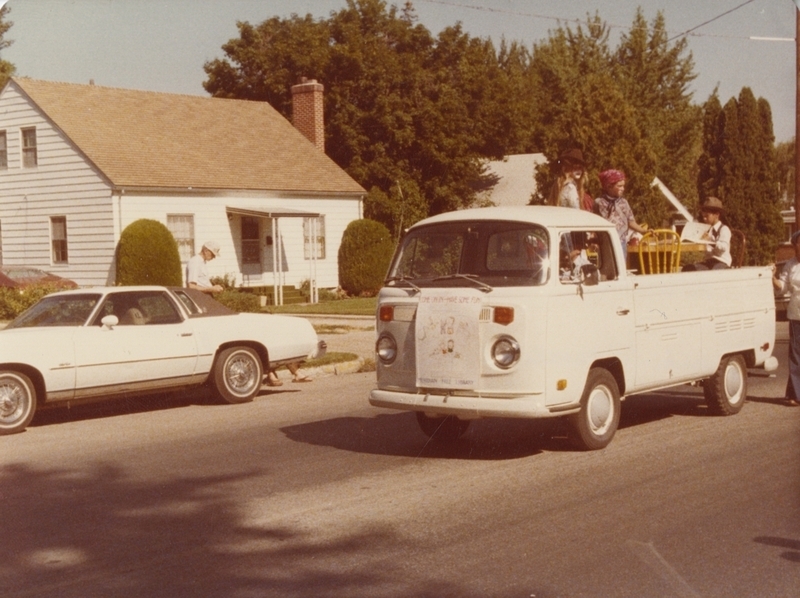 Meridian's 75th Birthday Parade, July 27, 1978. Everett Arndt drives the "Wagon Works" truck, while Chris Kennedy sits at the table reading. Sarah (last name unknown) is one of the other children in the back of the truck. 