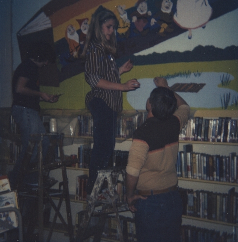 Individuals gather to help create a mural for the Meridian Library wall