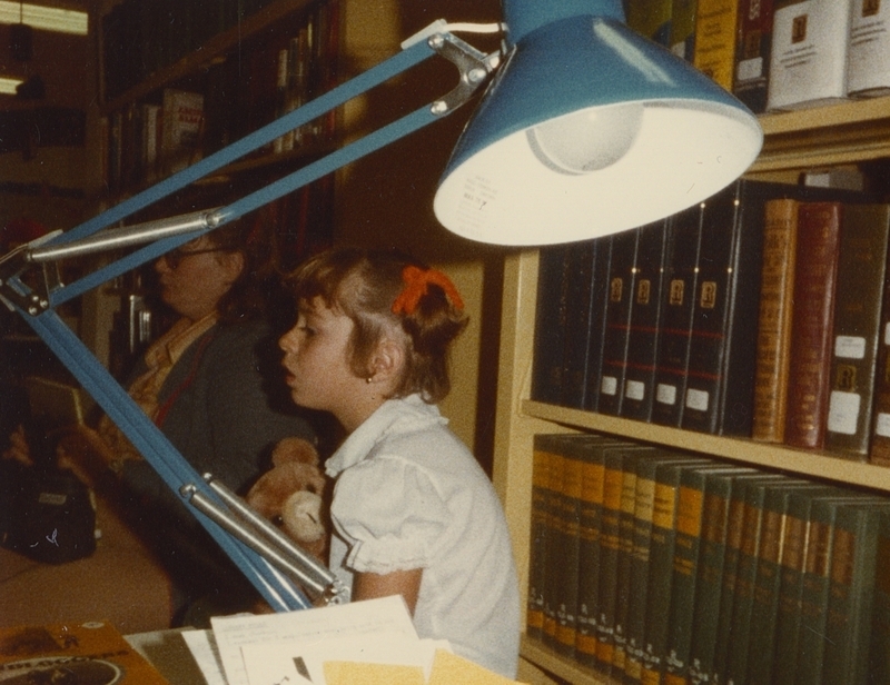 Little girl listens to storytime holding her teddy bear, October 27, 1982.