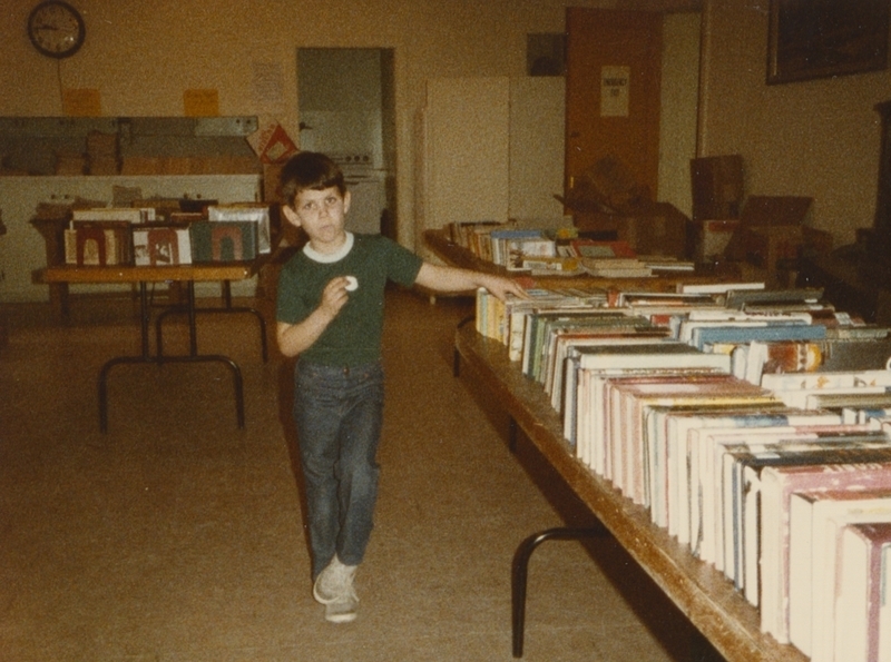 Boy stands near books at the Friends of the Meridian Library Book Sale.