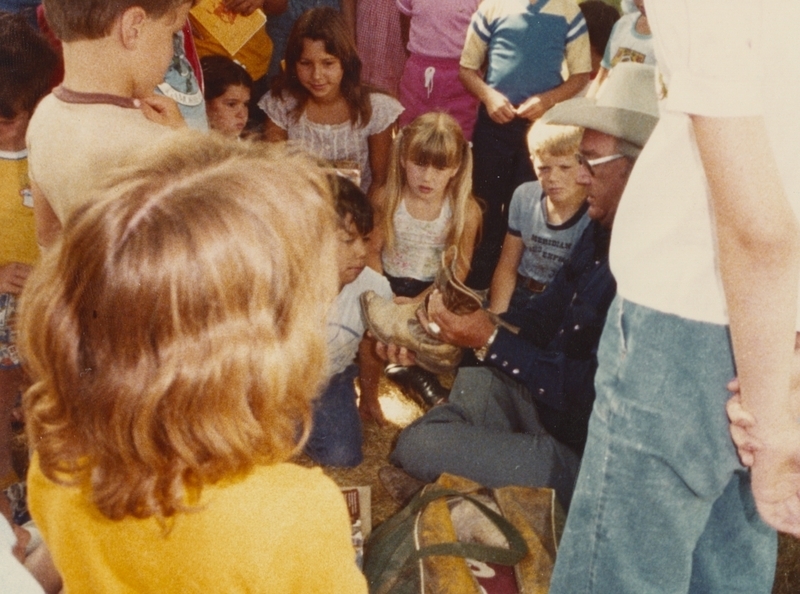 Retired rodeo announcer T.H. Bird shows a cowboy boot to children during a library event. 