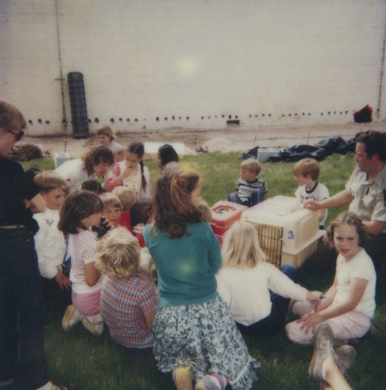 Children gathered around animal carriers on the library lawn with Bob Gregory from the Boise animal shelter. The program was part of Be Kind to Animals Week by the Boise animal shelter. At the side of the lawn you can see the state of the library expansion.