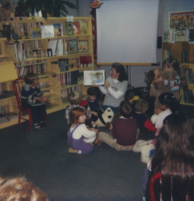 Children sit on floor with their teddy bears to listen to Good Bear Day storytime. 