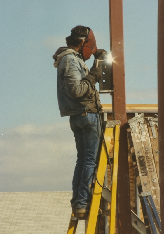 Construction worker welds on a ladder during the building of the Cherry Lane Library. 