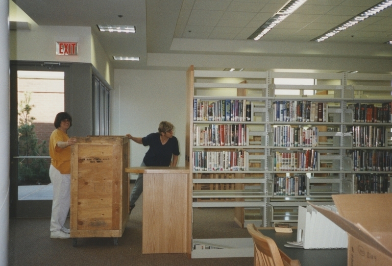 Library workers roll in a wooden crate of books to shleve at the new Cherry Lane Library building. 