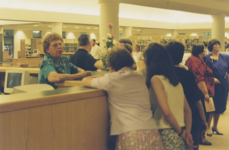 Librarian talks with patrons at the Cherry Lane Library front desk during the library's open house. 