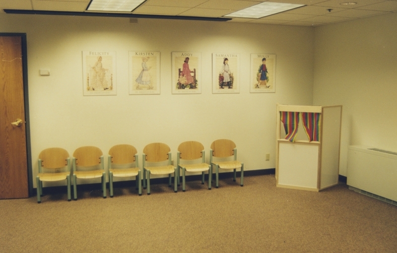 Portion of Cherry Lane Library's Children's Section during the open house. On the wall hangs American Girl posters, and in the corner sits a puppet stage. 