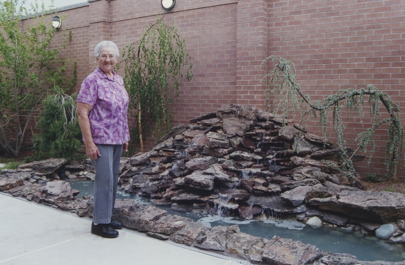 Librarian poses next to the Cherry Lane Library patio fountain at the library's open house. 