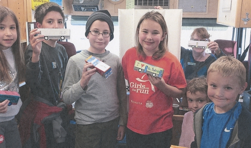 Children hold up their crafted mini-bookmobiles, circa 2016.